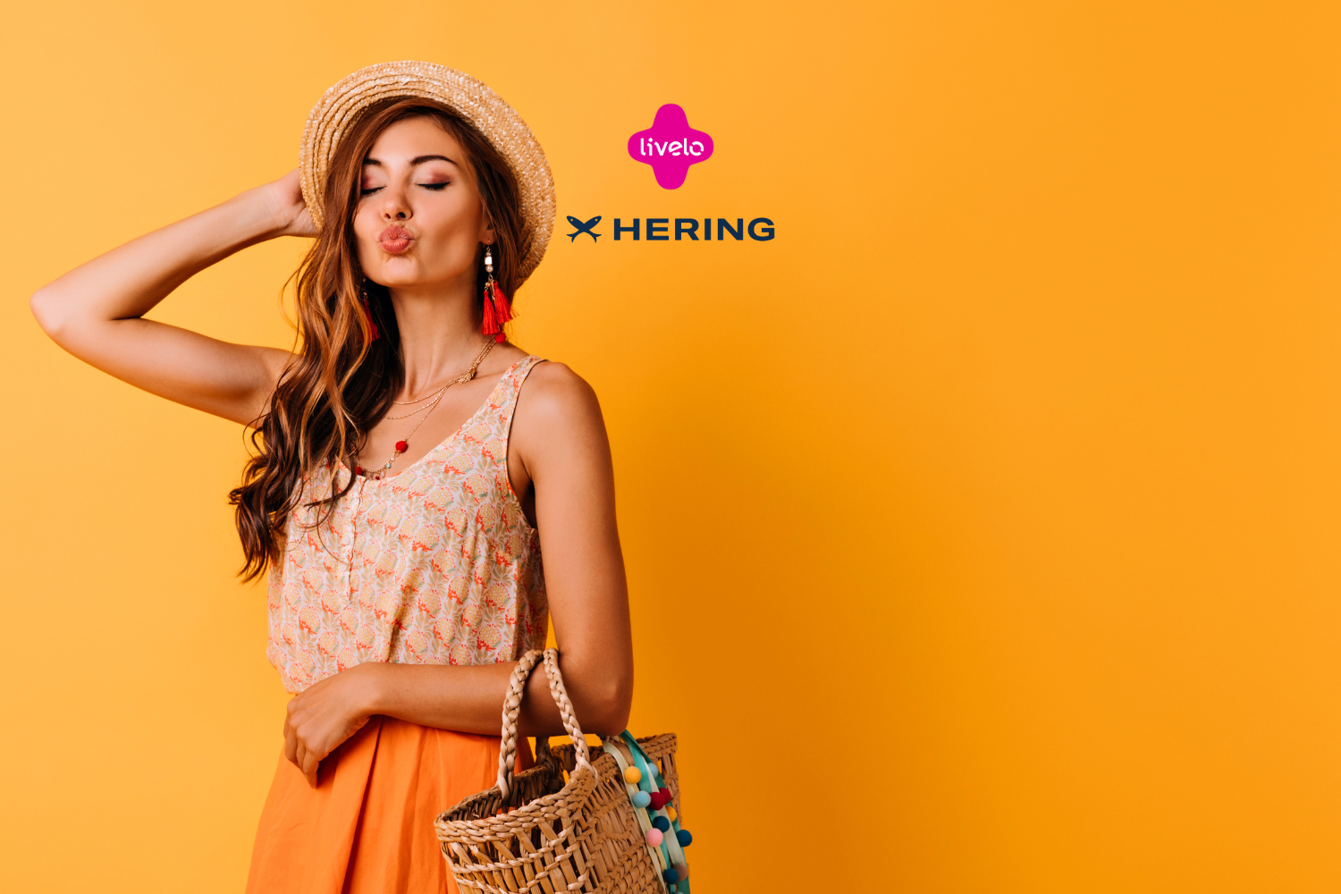 Mulher jovem, vestida de forma leve e casual, usando chapéu de palha e bolsa de vime, fazendo um biquinho e posando contra um fundo amarelo vibrante. Acima dela, estão os logos da Livelo e da Hering, sugerindo uma parceria de moda e estilo.