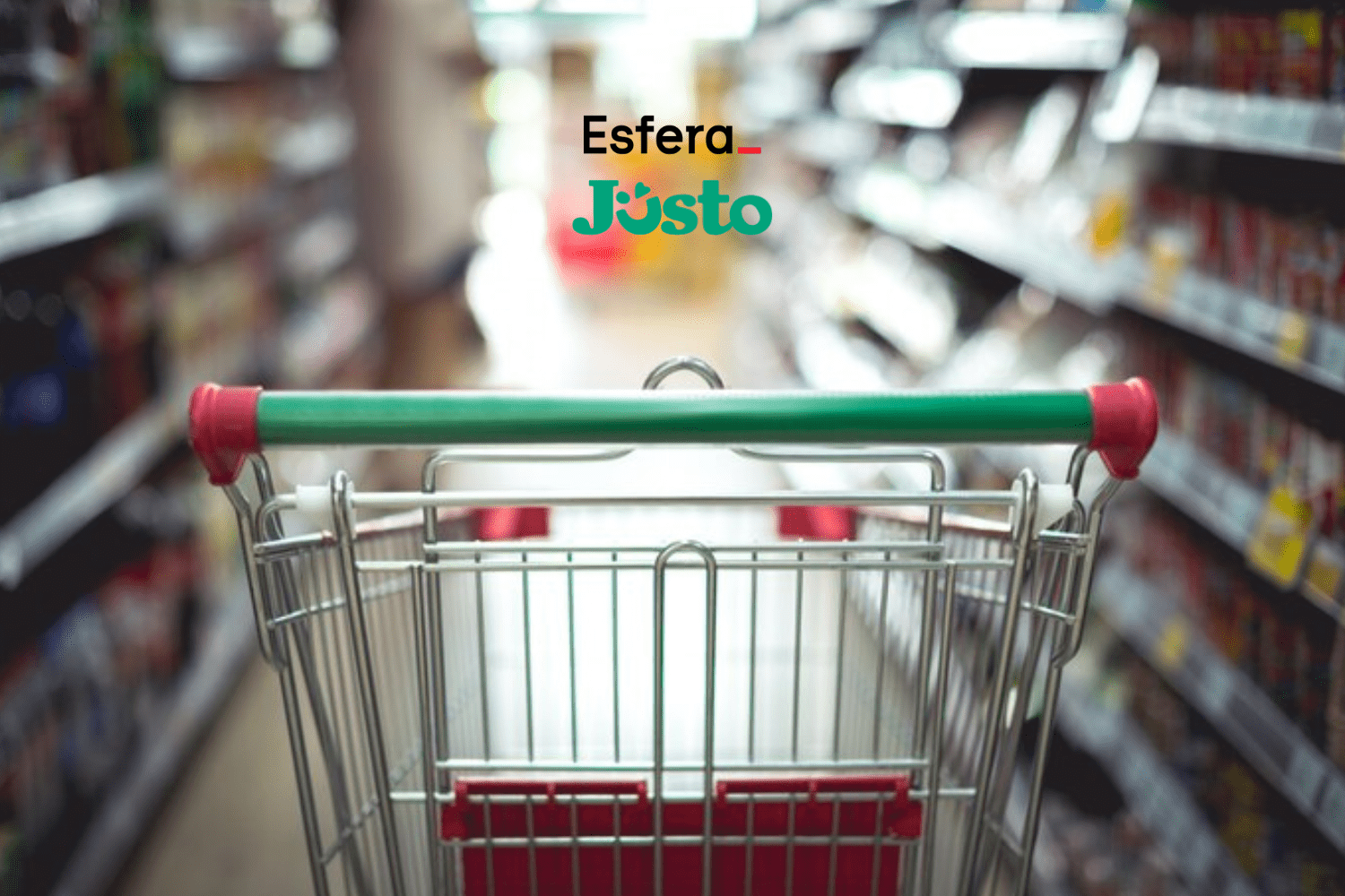 Carrinho de supermercado vazio, visto de trás, em um corredor de supermercado desfocado. Acima do carrinho, estão os logos da Esfera e do Justo, sugerindo uma parceria relacionada a compras e supermercados.