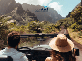 Casal dirigindo em um conversível por uma estrada cercada por vegetação exuberante e montanhas ao fundo. Acima deles, está o logo do programa de vantagens TudoAzul, sugerindo uma viagem cheia de aventuras e descobertas.