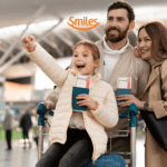 Uma família feliz no aeroporto. Uma menina empolgada aponta para algo à frente enquanto é empurrada em um carrinho de bagagem por seus pais, que sorriem ao lado dela. Todos estão segurando passaportes e passagens aéreas. A logo da "Smiles" está posicionada acima da imagem.