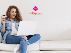 Uma mulher jovem, sentada em um sofá branco, está usando um laptop no colo e segurando um cartão de crédito na mão, com uma expressão de surpresa e alegria. Acima dela, no centro da imagem, estão as logos da Livelo e do AliExpress
