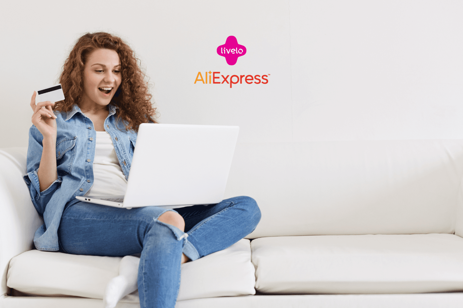 Uma mulher jovem, sentada em um sofá branco, está usando um laptop no colo e segurando um cartão de crédito na mão, com uma expressão de surpresa e alegria. Acima dela, no centro da imagem, estão as logos da Livelo e do AliExpress