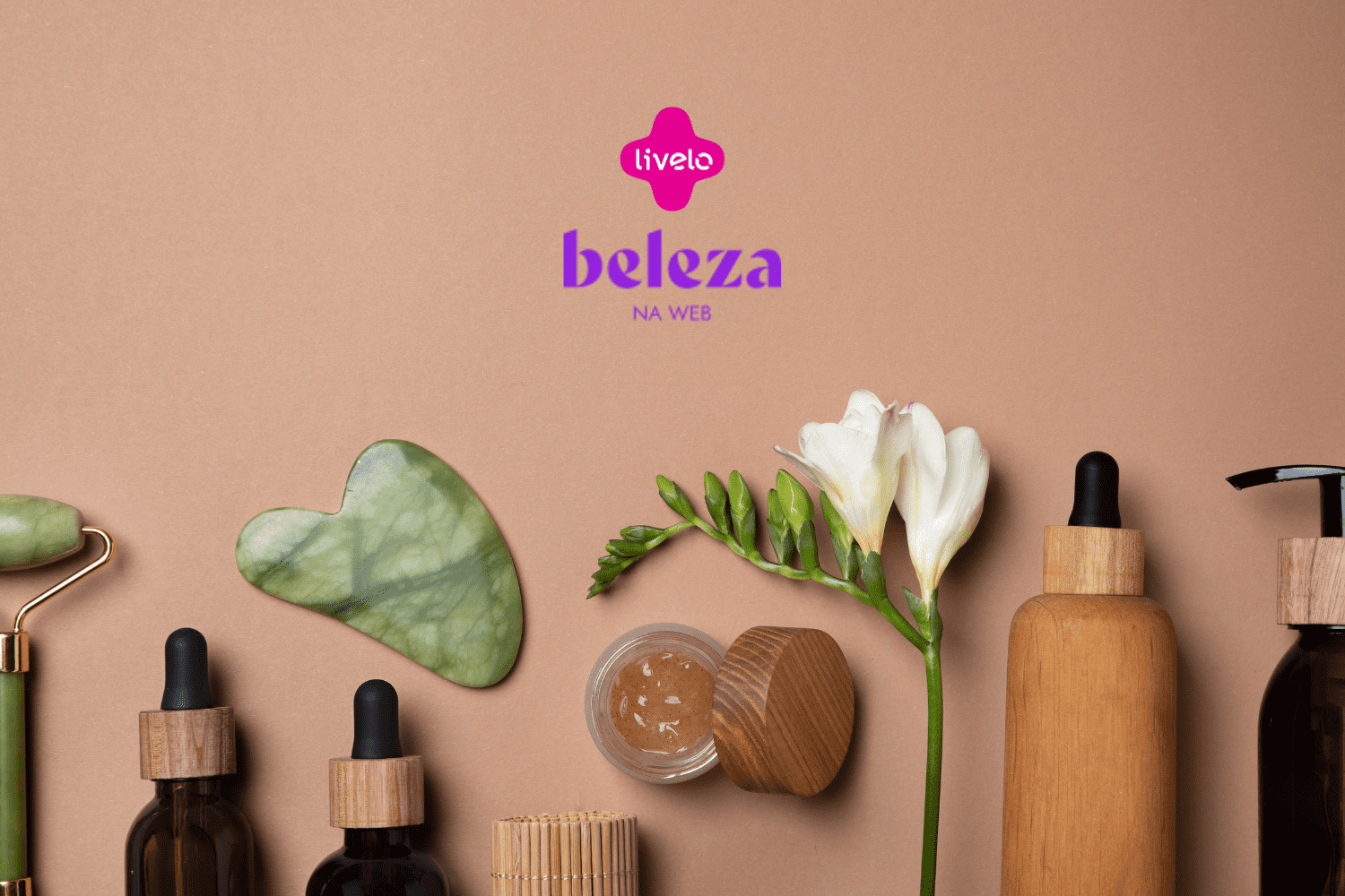 Uma composição de produtos de beleza e cuidados pessoais está disposta sobre uma superfície bege. Entre os itens, há frascos de vidro e madeira, um rolo de jade, uma ferramenta de massagem facial em formato de coração e uma flor branca. No centro da imagem, acima, estão as logos da Livelo e Beleza na Web.