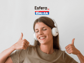 Imagem de uma mulher jovem sorrindo, usando fones de ouvido brancos e fazendo um sinal de "joinha" com as duas mãos. Acima da imagem, estão as logos da Esfera e das Casas Bahia.