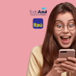 **Texto alternativo:** Imagem de uma jovem mulher de cabelos longos e óculos redondos, com expressão de surpresa e alegria enquanto olha para o celular. Ao fundo, uma parede rosa. Acima da imagem, estão as logos do programa de vantagens TudoAzul e do banco Itaú.