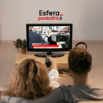 **Texto alternativo:** Imagem de um casal assistindo televisão em uma sala de estar. A TV está transmitindo uma reportagem ao vivo com o título "Breaking News". Acima da TV, estão as logos da Esfera e do Ponto Frio.