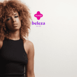 Descrição alternativa curta: Mulher com cabelo cacheado volumoso e maquiagem destacada, olhando para a câmera. Logotipo da Livelo e Beleza na Web acima.