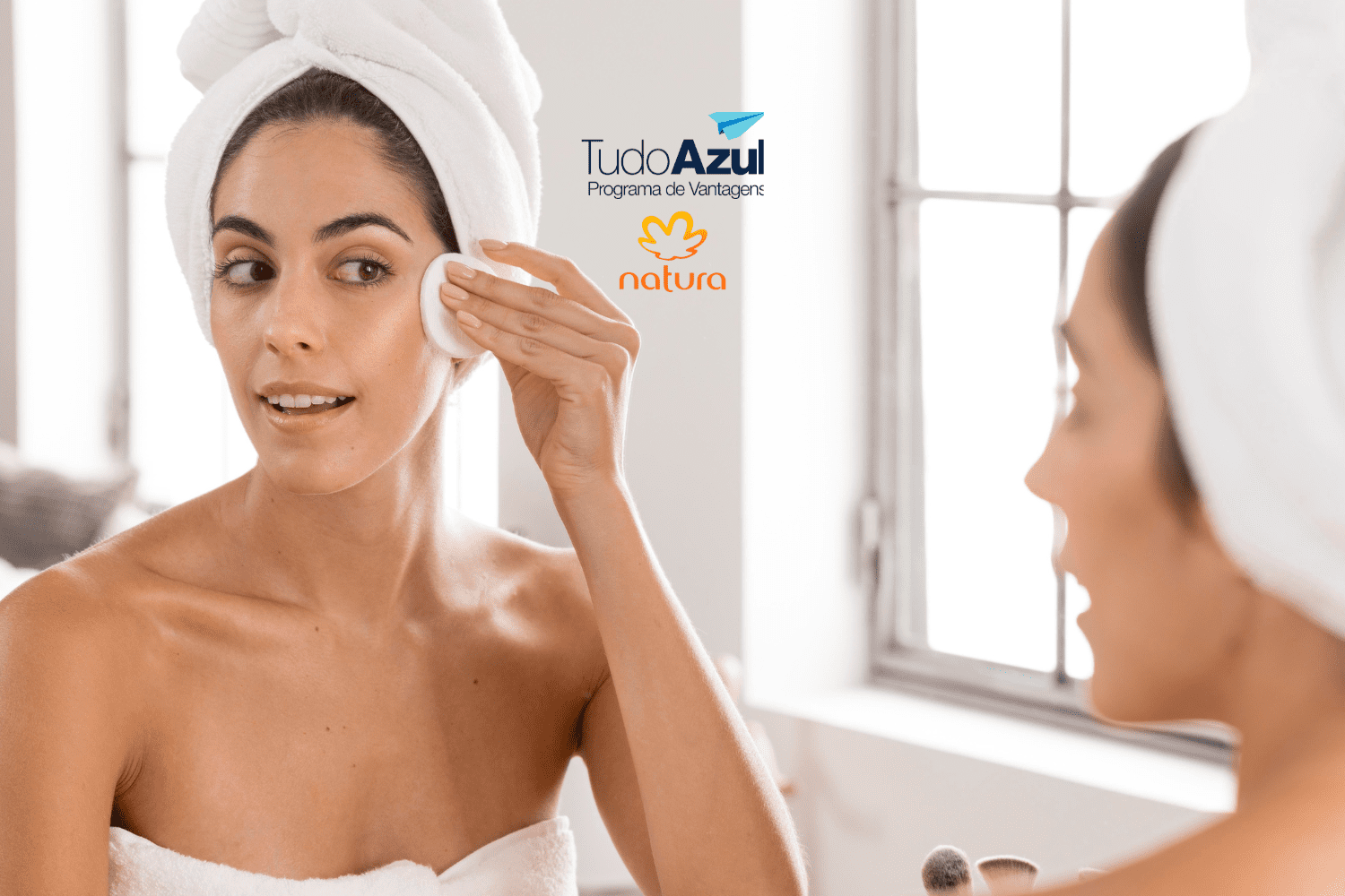 Mulher em um ambiente de banheiro aplicando um produto na pele com algodão, enquanto usa toalha na cabeça. Ao lado, os logotipos do programa de vantagens TudoAzul e da marca Natura.