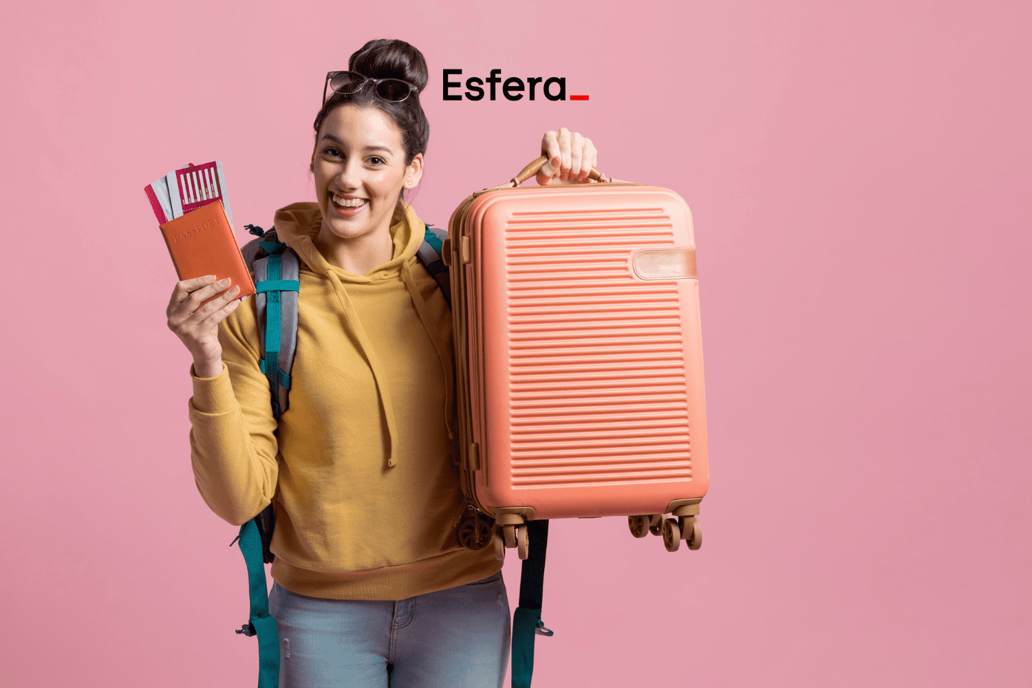 Descrição alternativa curta: Mulher sorridente, vestindo moletom amarelo e mochila verde, segurando uma mala cor de pêssego e um passaporte com passagens. Ao fundo, um fundo rosa e o logotipo da Esfera na parte superior da imagem.