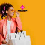 Na imagem, uma mulher sorridente, vestida com um blazer rosa e segurando sacolas de compras, posa contra um fundo amarelo vibrante. Ela está usando óculos de sol amarelos e um lenço colorido amarrado no cabelo, que complementa seu visual moderno e estiloso. No centro superior da imagem, os logotipos da Livelo e da Insider estão visíveis, indicando uma colaboração ou promoção entre as marcas.