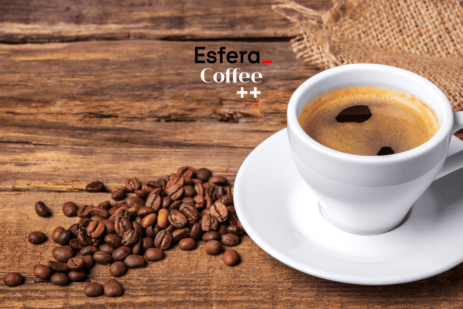 Uma xícara de café espresso sobre um pires branco está posicionada à direita da imagem, sobre uma superfície de madeira. Ao lado, alguns grãos de café estão espalhados. No canto superior esquerdo, estão as logos da Esfera e Coffee++