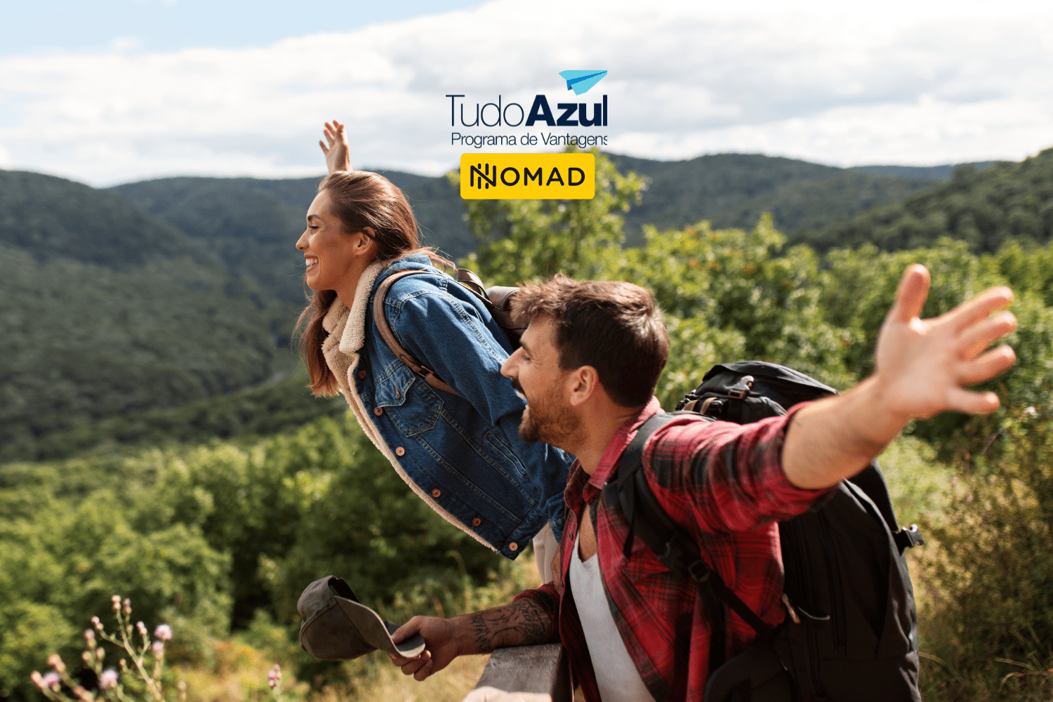 Um casal jovem está sorrindo e com os braços abertos, em uma área montanhosa e arborizada, transmitindo sensação de liberdade. Ambos estão com mochilas, sugerindo uma viagem de aventura. No topo da imagem, estão as logos do "Tudo Azul Programa de Vantagens" e "Nomad".