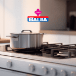 Uma panela de aço inoxidável está sobre um fogão moderno de quatro bocas, em uma cozinha bem iluminada e minimalista. No topo da imagem, aparecem as logos da "Livelo" e "Casas Bahia".