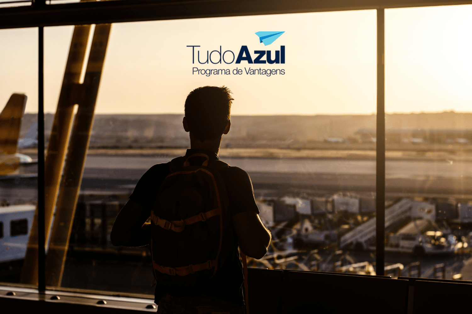 Um viajante com mochila observa o pôr do sol através das grandes janelas de um aeroporto, com a pista e aviões ao fundo. No topo da imagem, está a logo do "Tudo Azul - Programa de Vantagens"