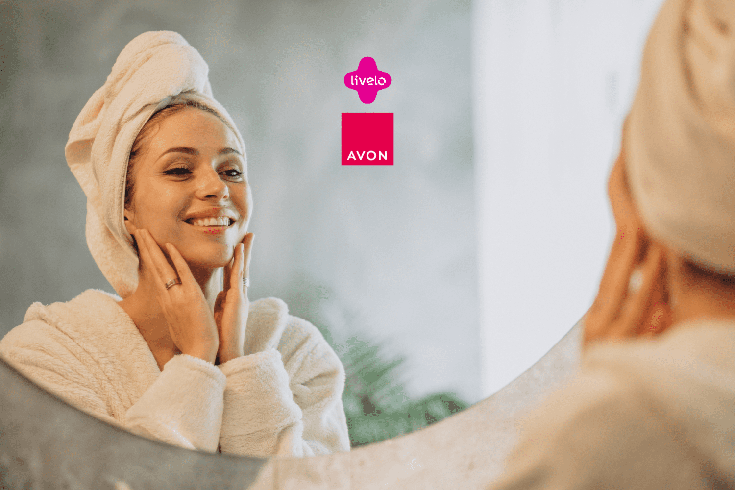 Imagem de uma mulher sorridente, em frente ao espelho, aplicando produtos faciais com as mãos. Ela está vestida com um roupão branco felpudo e uma toalha enrolada na cabeça, transmitindo uma sensação de autocuidado e bem-estar. No centro da imagem estão as logos da Livelo e da Avon.