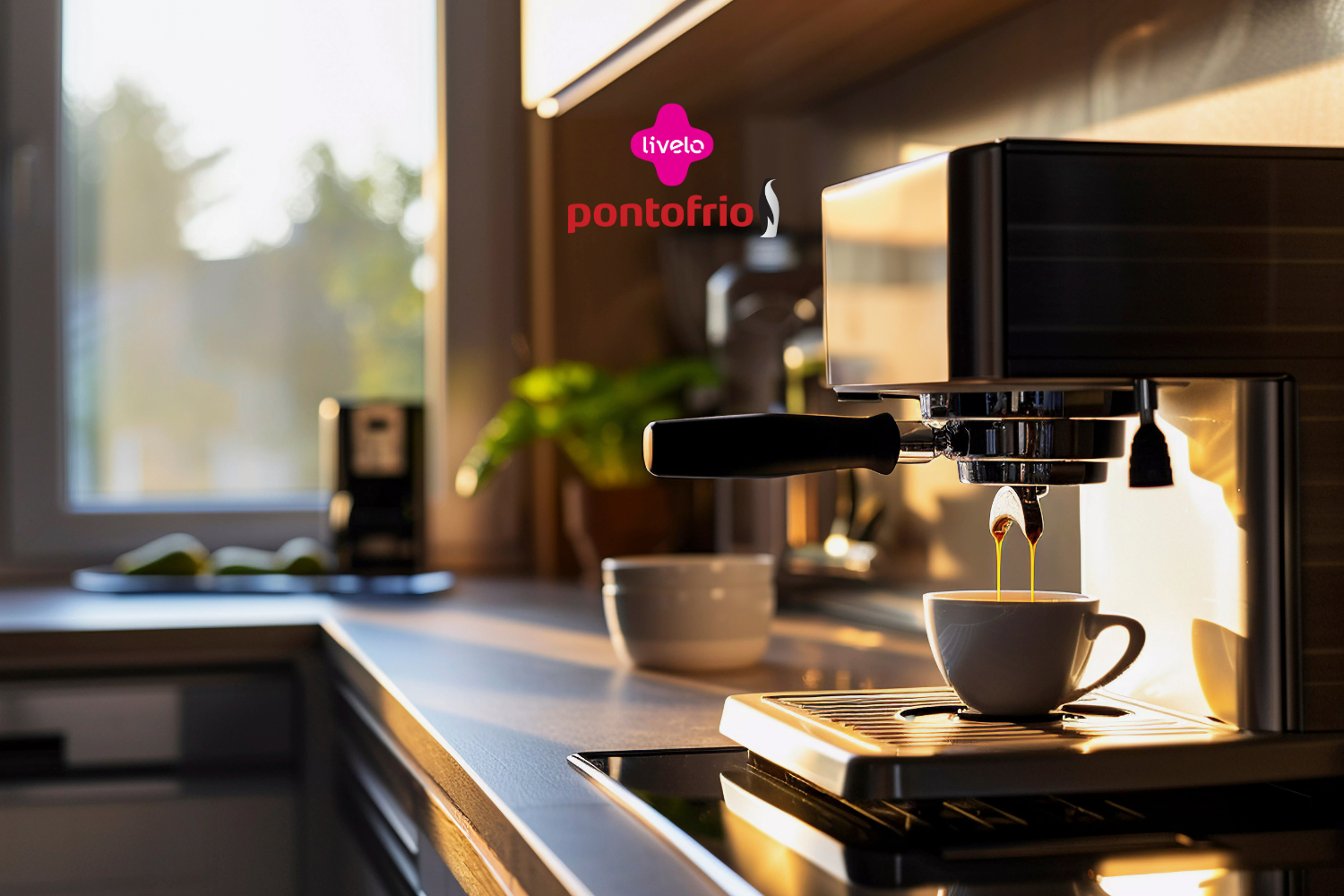 Imagem de uma cafeteira expresso em uma cozinha iluminada pela luz suave do amanhecer, com uma xícara branca posicionada sob o fluxo de café. O ambiente transmite uma sensação acolhedora e tranquila. No topo da imagem, aparecem as logos da Livelo e do Ponto Frio.