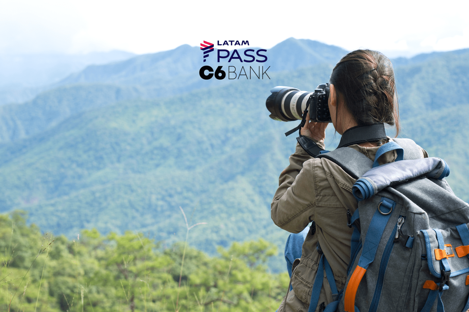 "Uma jovem fotógrafa, equipada com uma mochila e uma câmera profissional, fotografa a paisagem montanhosa à sua frente. O cenário é composto por montanhas verdes sob um céu claro, transmitindo tranquilidade e conexão com a natureza. Acima da imagem, estão os logotipos da LATAM Pass e C6 Bank, sugerindo uma parceria que oferece benefícios para viajantes e entusiastas da fotografia ao ar livre."
