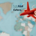 A imagem mostra uma mão segurando um pequeno avião de brinquedo vermelho, que é destacado contra um fundo desfocado de um mapa-múndi. No canto superior esquerdo, estão os logotipos do "TudoAzul Programa de Vantagens" e da "Esfera".
