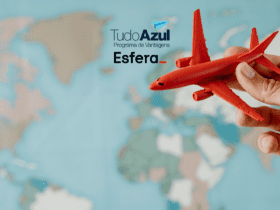 A imagem mostra uma mão segurando um pequeno avião de brinquedo vermelho, que é destacado contra um fundo desfocado de um mapa-múndi. No canto superior esquerdo, estão os logotipos do "TudoAzul Programa de Vantagens" e da "Esfera".
