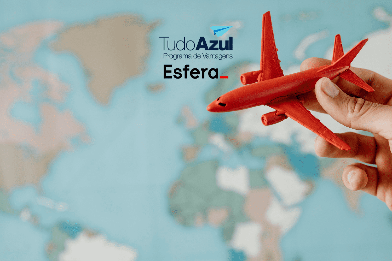 A imagem mostra uma mão segurando um pequeno avião de brinquedo vermelho, que é destacado contra um fundo desfocado de um mapa-múndi. No canto superior esquerdo, estão os logotipos do "TudoAzul Programa de Vantagens" e da "Esfera".
