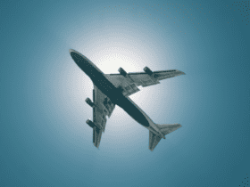 Avião em voo visto de baixo, com o sol iluminando o céu azul claro ao fundo, capturando o momento de decolagem ou aterrissagem. aeroporto de porto alegre