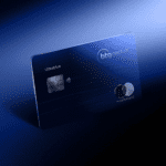 Cartão Ultrablue BTG Pactual com design sofisticado em metal, na cor azul, com o logotipo BTG Pactual e bandeira Mastercard Black em destaque. O cartão está inclinado em um fundo gradiente azul escuro, reforçando sua imagem de exclusividade.