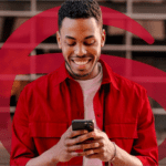 Homem sorrindo enquanto utiliza o celular, destacando a praticidade e conveniência dos serviços digitais oferecidos, com um fundo moderno e elementos gráficos do Bradesco em vermelho.