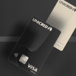 Imagem de dois cartões Unicred Visa Infinite sobre um fundo escuro. O cartão preto está em primeiro plano, enquanto o cartão dourado aparece ao fundo